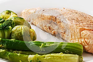 Grilled red fish steak with brussels sprouts and asparagus in a plate on an isolated white background