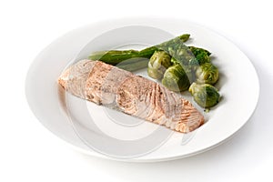 Grilled red fish steak with brussels sprouts and asparagus in a plate on an isolated white background