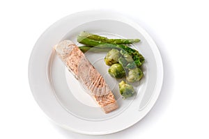 Grilled red fish steak with brussels sprouts and asparagus in a plate on an isolated white background