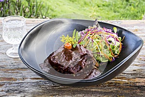 Grilled rib eye beef steak with vegetable salad in black bowl