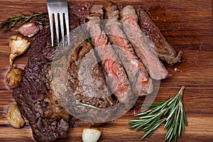 Grilled rib-eye steak of marble beef closeup with spices on a wooden Board. Juicy steak medium rare, sliced and ready to eat