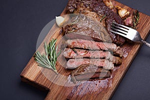 Grilled rib-eye steak of marble beef closeup with spices on a wooden Board. Juicy steak medium sliced and ready to eat. With copy