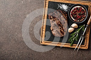 Grilled rib eye steak, spices and vintage meat fork on serving b