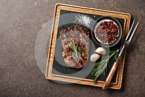 Grilled rib eye steak, spices and vintage meat fork on serving b