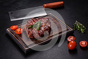 Grilled ribeye beef steak, herbs and spices on a dark table