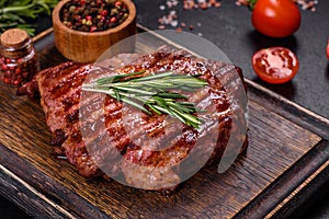 Grilled ribeye beef steak, herbs and spices on a dark table