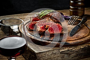 Grilled ribeye beef steak with red wine, herbs and spices on wooden table