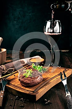 Grilled ribeye beef steak with wine, knife and fork on a wooden Board. Whole roast piece of meat