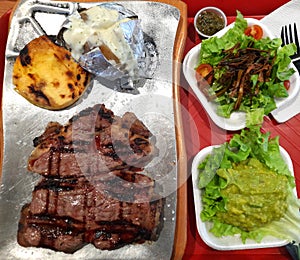 Grilled ribeye steak with baked potato and vegetables