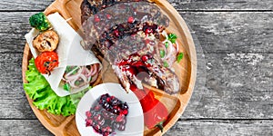 Grilled Ribeye Steak on bone with berry sauce, fresh salad and grilled vegetables on cutting board on wooden background