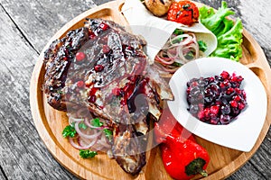 Grilled Ribeye Steak on bone with berry sauce, fresh salad and grilled vegetables on cutting board on wooden background