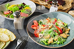 Grilled ribs with buckwheat, salad with citrus and grilled chicken liver, salad with tomato. Table with food in restaurant.