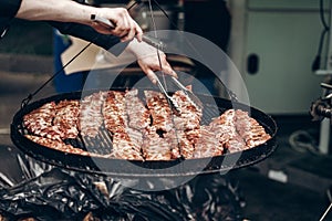 grilled ribs meat. man holding steel tongues and roasting beef p