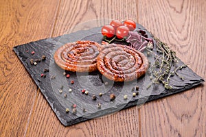 Grilled ring sausages on slate plate with cherry tomatoes and grren