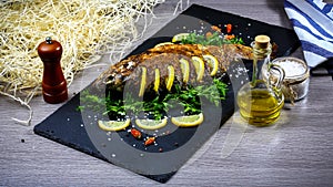 Grilled river fish on a plate with lemon and baked vegetables and parsley. Food recipe photo, copy text