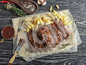 Grilled roast pork ribs with sauce , french fries, spices, wooden background