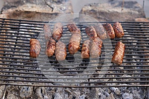 Grilled Romanian meat rolls on a barbecue grid.