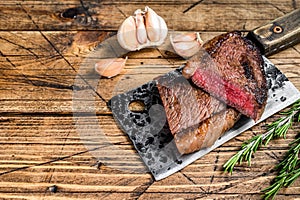 Grilled rump cap or brazilian picanha beef meat steak on a cleaver. wooden background. Top view. Copy space