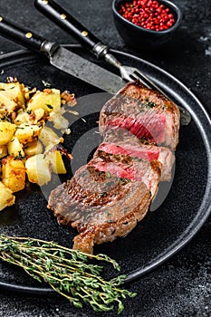Grilled rump steak with potato, beef meat. Black background. Top view