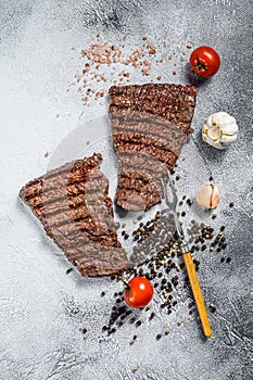 Grilled rump steak with spices. BBQ beef. Gray background. Top view