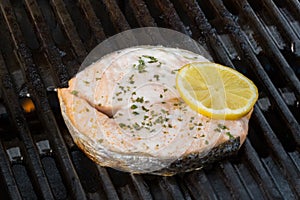 Grilled salmon decorated with a sliced lemon fruit on a grill