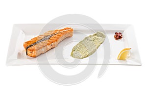 Grilled salmon fillet with lemon and guacamole sauce on white plate isolated on white background