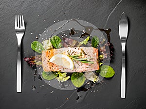 Grilled salmon fillet with salad on black