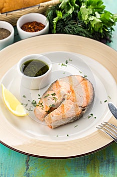 Grilled salmon fillet with soy sauce and slice of lemon on blue wooden table