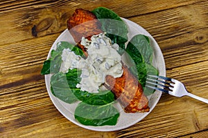 Grilled salmon fillet with spinach and tartare sauce on wooden table. Top view