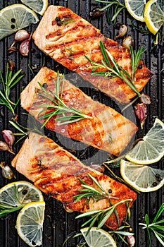 Grilled salmon fillets sprinkled with fresh herbs and lemon juice on a grill plate