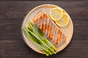 Grilled salmon with lemon, asparagus on the wooden background