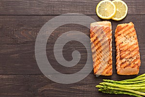 Grilled salmon with lemon, asparagus on wooden background