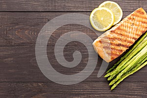 Grilled salmon with lemon, asparagus on wooden background