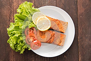 Grilled salmon with lemon,tomato on the wooden background