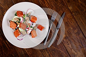 Grilled salmon with radish and spinach, served on white plate. View from above, top studio shot