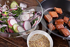 Grilled salmon with radish and spinach, served on wooden table. View from above, top studio shot