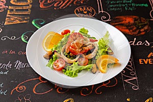 Grilled salmon  Salad of fresh vegetables and seafood in a plate on a table in