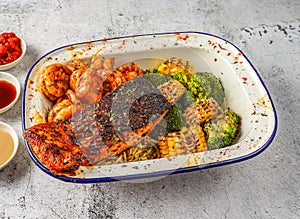 Grilled salmon and shrimps with noodles, grilled corn and broccoli served in isolated on grey background top view of singaporean