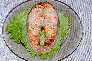 Grilled salmon steak laid on a transparent plate