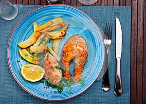 Grilled salmon steak served on plate with fried potato