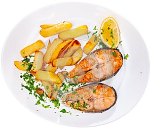 Grilled salmon steak served on plate with fried potato