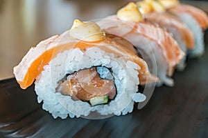 Grilled salmon sushi roll, japanese food style on black ceramic