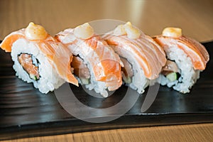 Grilled salmon sushi roll, japanese food style on black ceramic