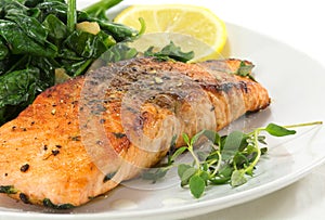 grilled salmon with thyme, lemon and spinach on white, vegetarian low carb dish, close up