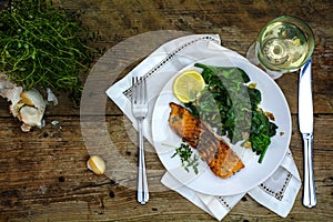 Grilled salmon with thyme, lemon, spinach and white wine on a da