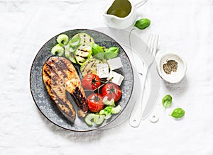 Grilled salmon, zucchini, baked cherry tomatoes and feta cheese - healthy balanced meal on light background