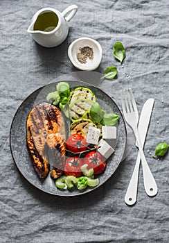 Grilled salmon, zucchini, baked cherry tomatoes and silky tofu - healthy balanced meal on grey background