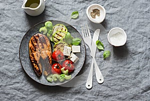 Grilled salmon, zucchini, baked cherry tomatoes and silky tofu - healthy balanced meal on grey background