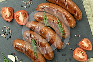 Grilled sausage with the addition of herbs and vegetables on the grill plate, outdoors