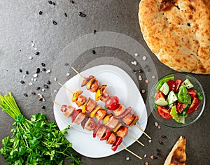 Grilled sausage with the addition of pepper and tomatoes on the grill plate, outdoors. Grilling food, vegetables salad